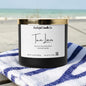 Candle with a label on a striped towel by the beach
