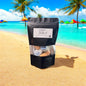 Black package with a label on a sandy beach with palm trees and colorful umbrellas in the background.