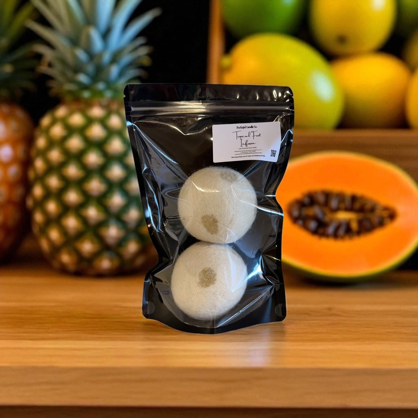 Two white spherical products in a black packaging bag on a wooden surface with fruits in the background.