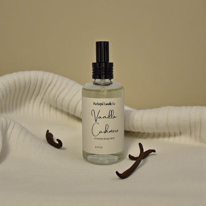 Bottle of Vanilla Cashmere scented body mist with vanilla beans on a beige background