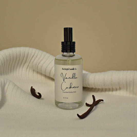 Bottle of Vanilla Cashmere scented body mist with vanilla beans on a beige background