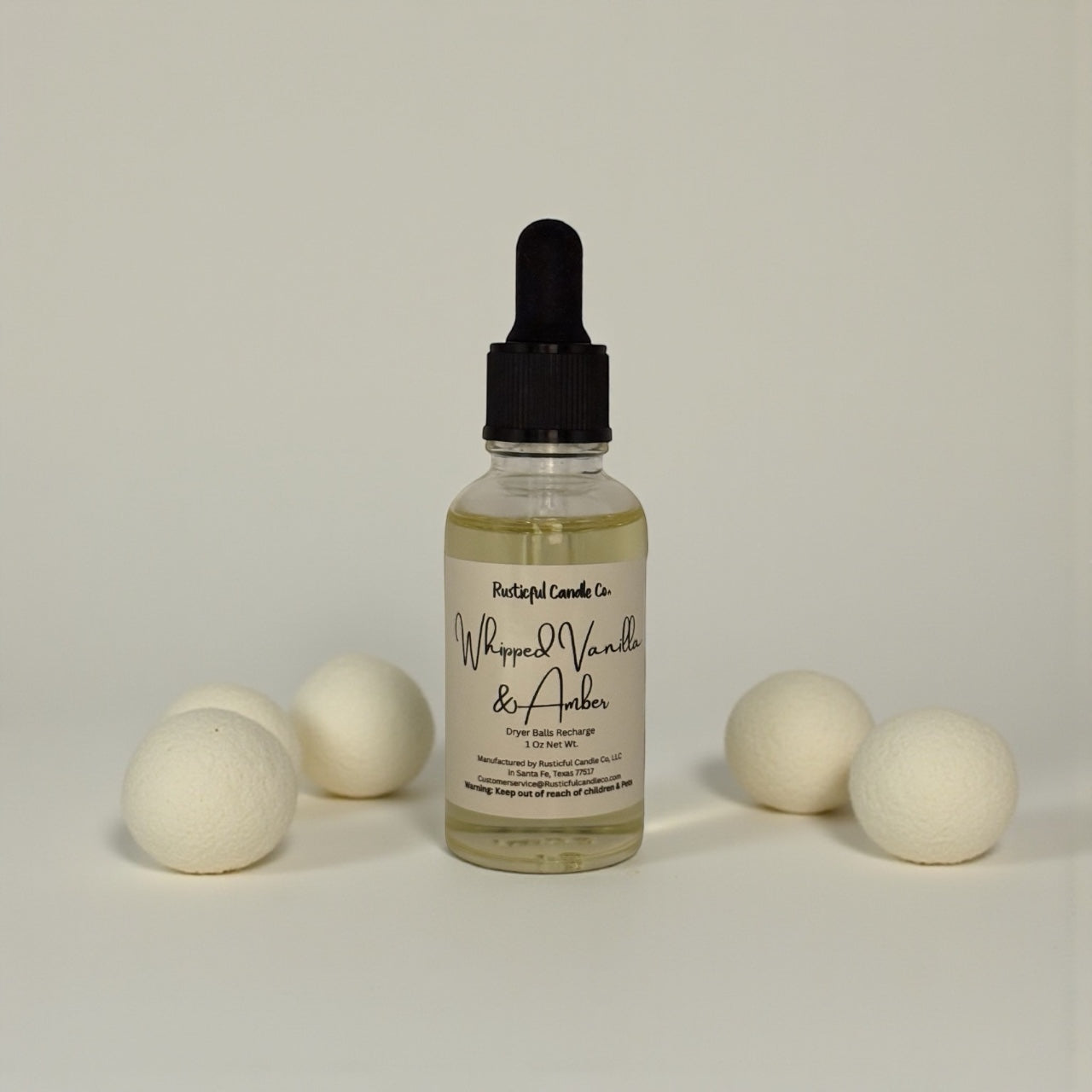 Bottle of 'Whipped Vanilla & Amber' soap bar fragrance with wooden beads on a neutral background
