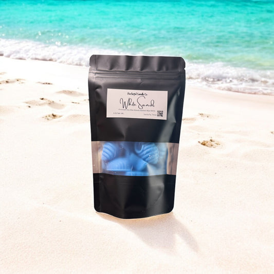 Black packaging of 'White Sand' on a beach with turquoise water.