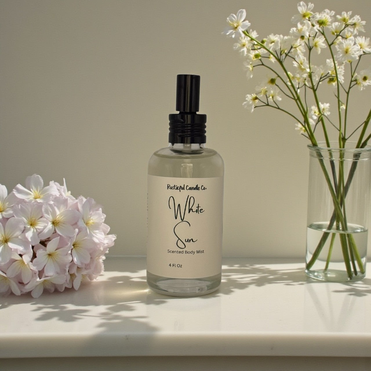 Bottle of 'White Sun' scented body mist with flowers on a surface