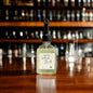 Bottle of 'Leather & Brandy' candle on a bar counter with blurred bottles in the background
